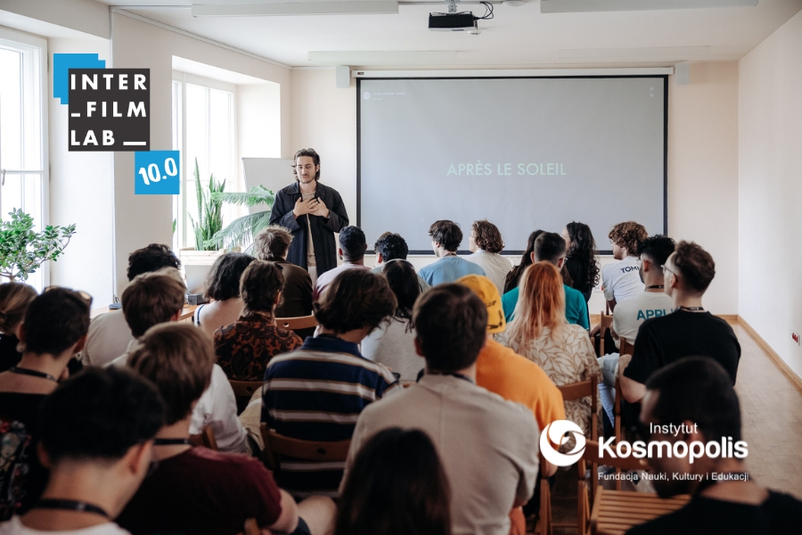 Warsztaty INTERFILMLAB. Pełna sala uczestników i uczestniczek. Logo INTERFILMLAB 10.0 i Instytutu KOSMOPOLIS Fundacja Nauki, Kultury i Edukacji.